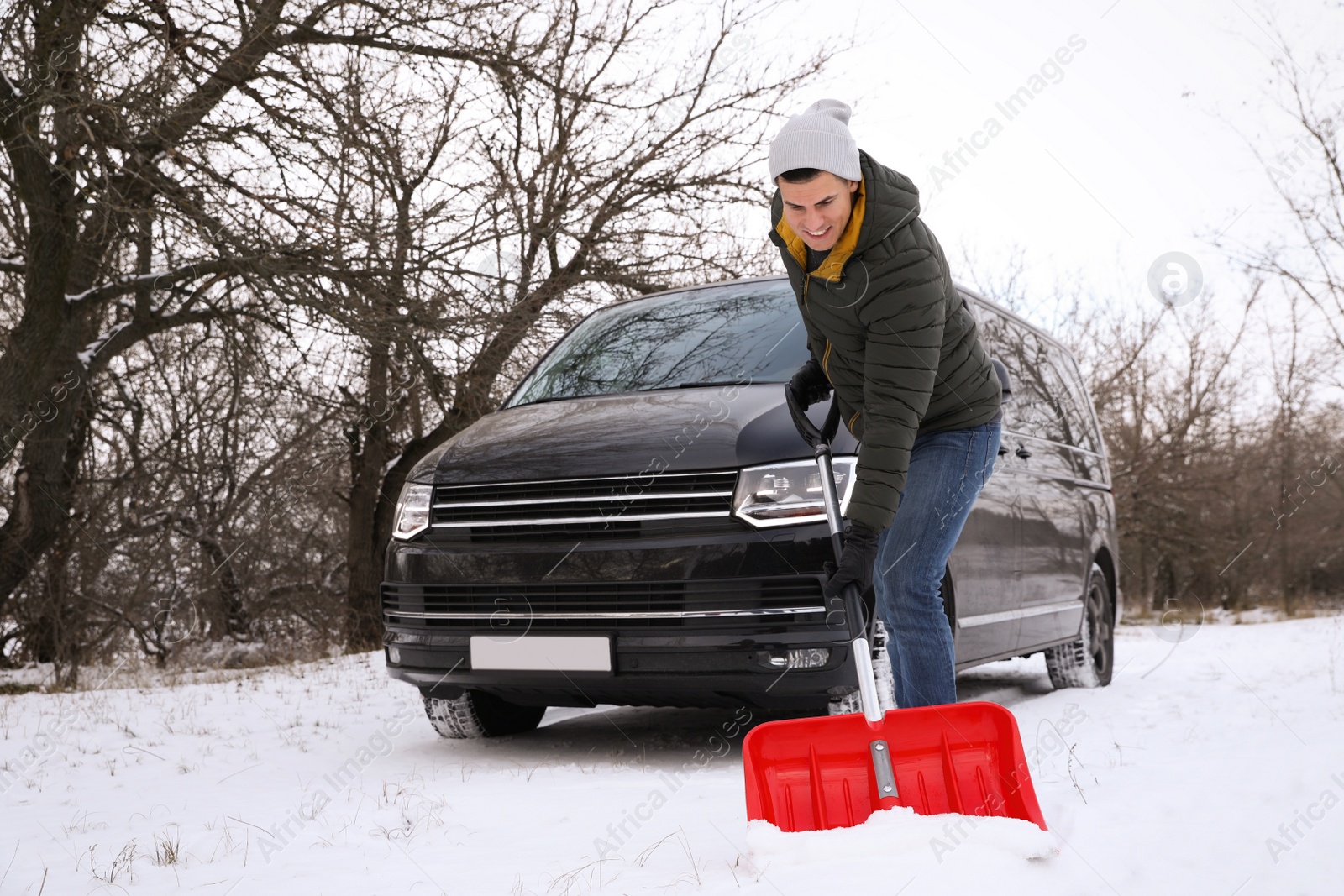 Photo of Man removing snow with shovel near car outdoors on winter day