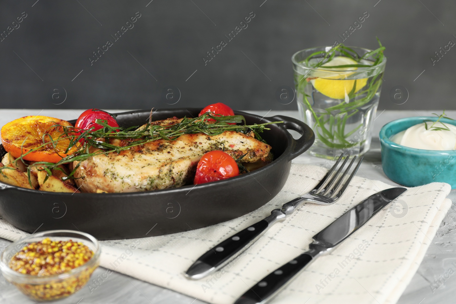 Photo of Tasty chicken, vegetables, drink with tarragon and salad dressings served on grey table