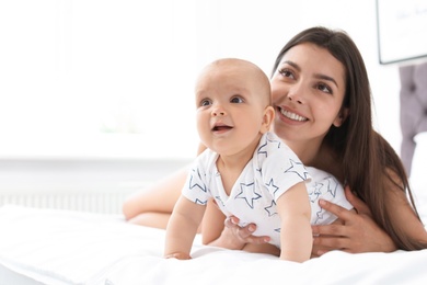 Young mother with her cute baby girl on bed at home