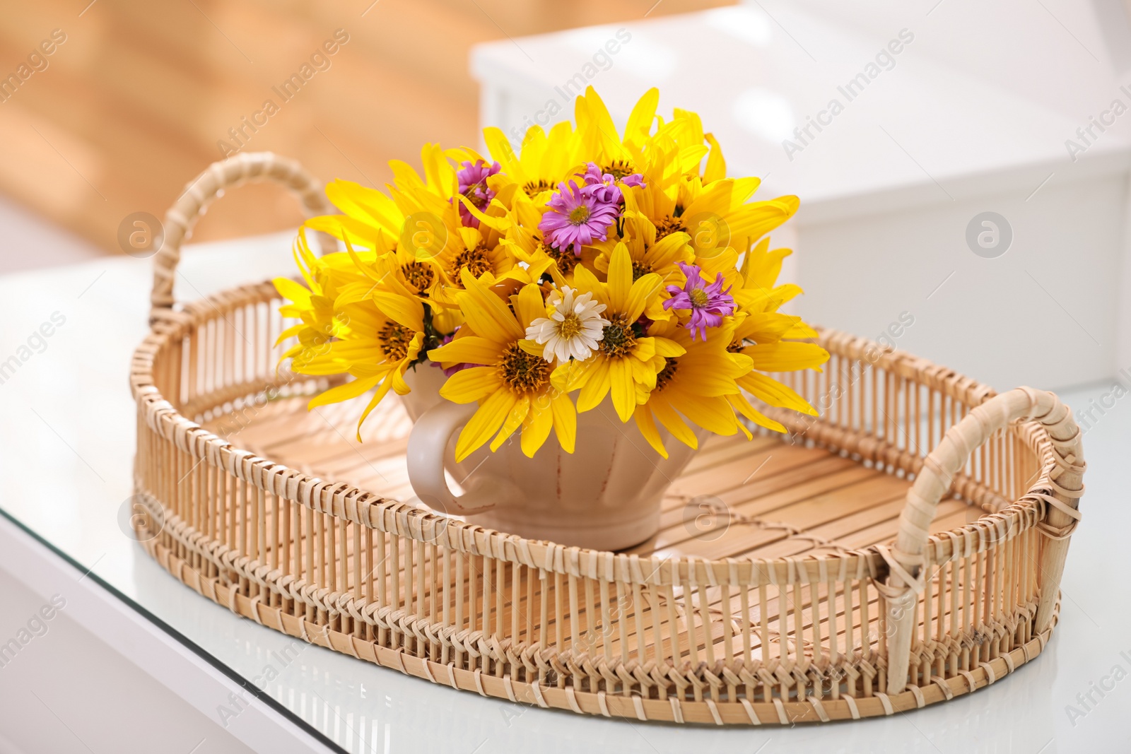 Photo of Cup with beautiful bright flowers in tray on table