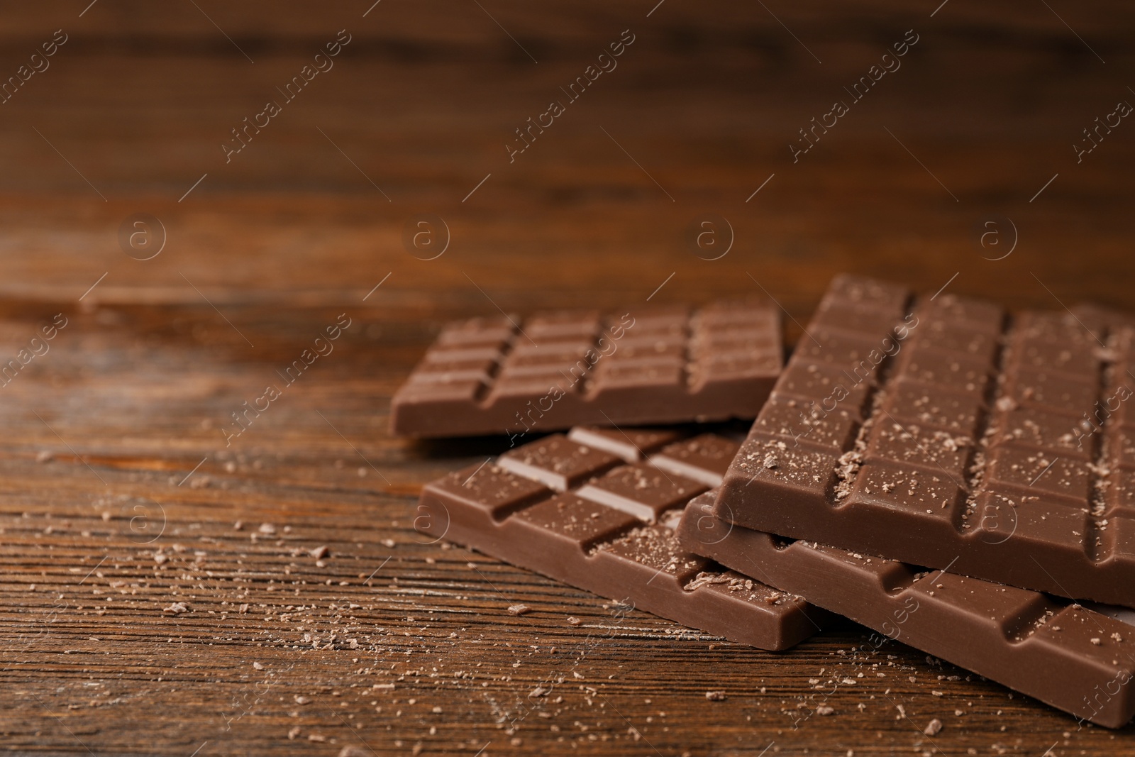 Photo of Tasty chocolate bars on wooden table, space for text
