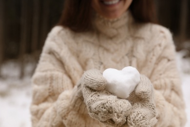 Photo of Woman holding heart made of snow, closeup view