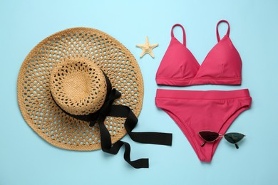 Stylish bikini, hat and sunglasses on light blue background, flat lay