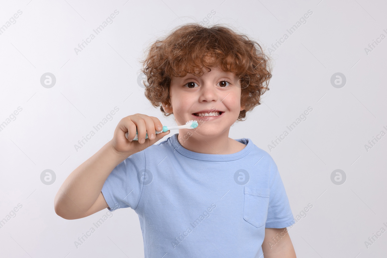 Photo of Cute little boy holding plastic toothbrush on white background