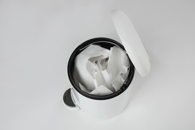 Trash bin with used toilet paper on white background