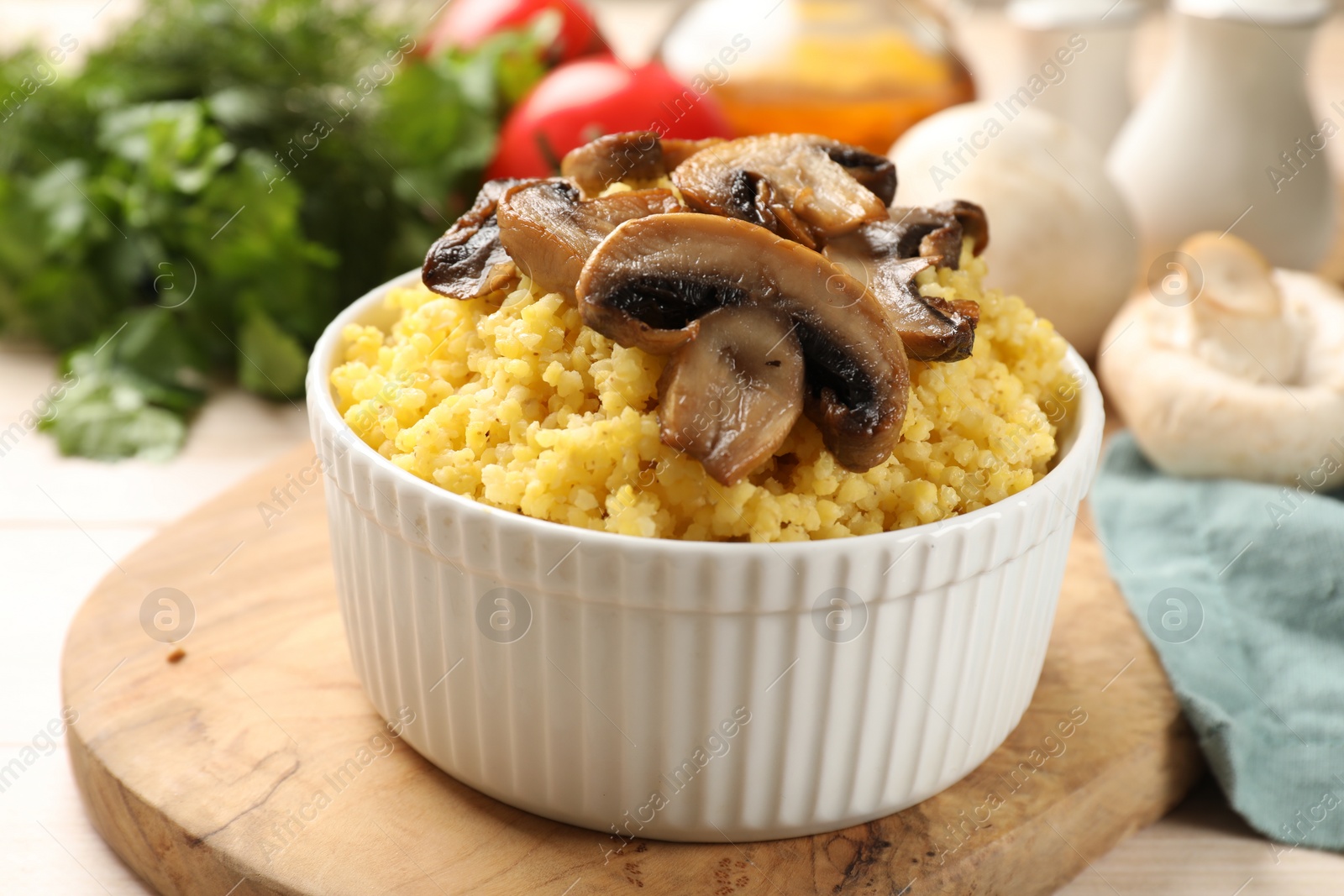 Photo of Tasty millet porridge and mushrooms in bowl on table, closeup