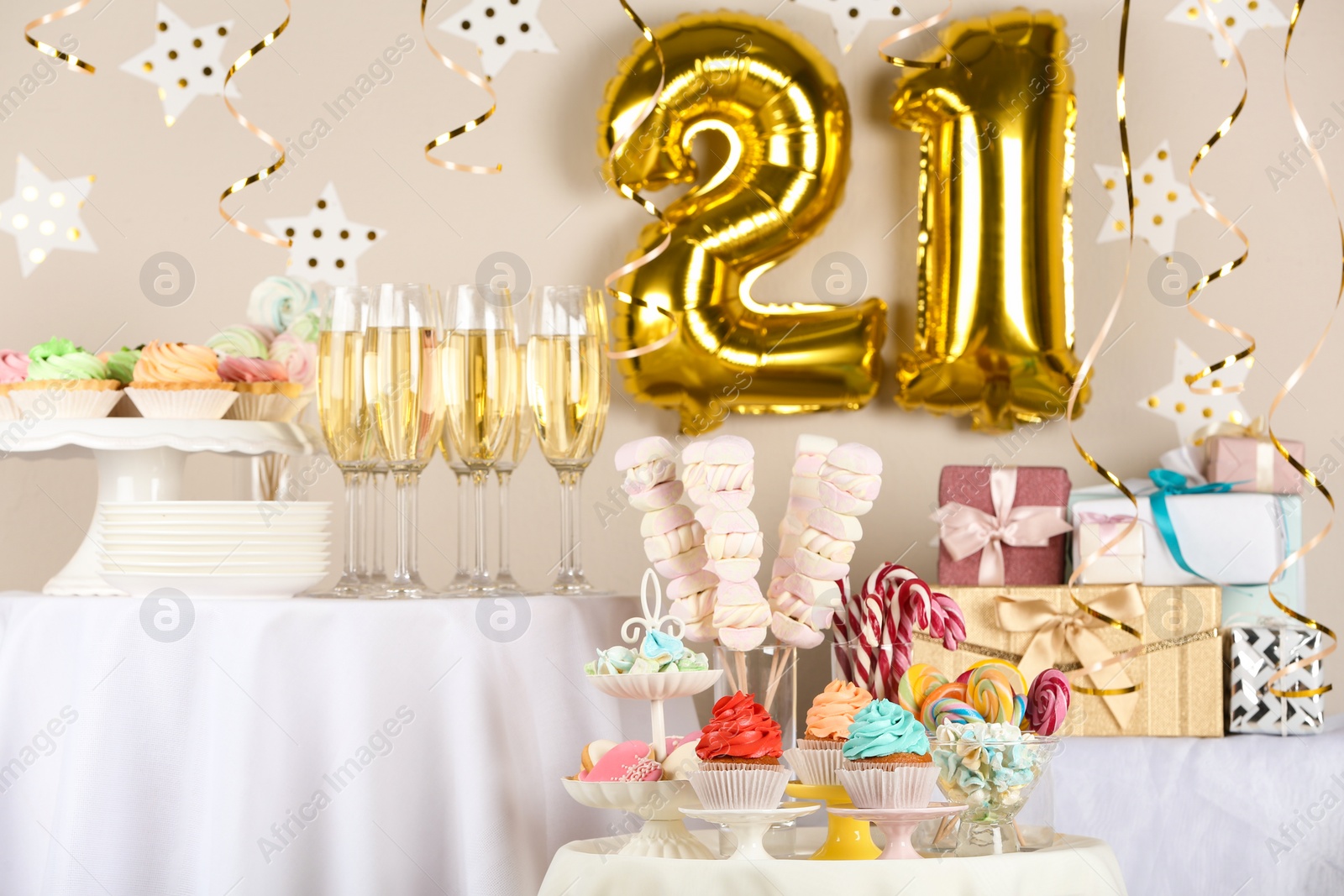 Photo of Dessert table in room decorated with golden balloons for 21 year birthday party