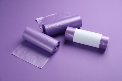 Photo of Rolls of color garbage bags on violet background