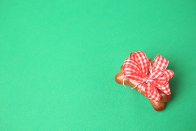 Photo of Bone shaped dog cookie with red bow on green background, above view. Space for text