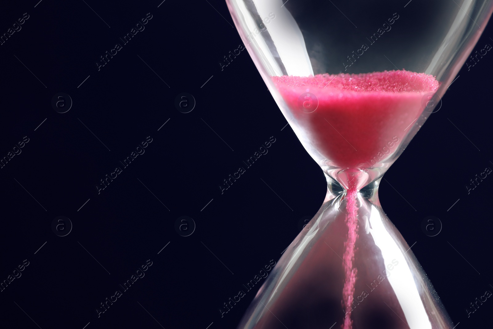 Photo of Hourglass with flowing sand on black background, closeup. Time management