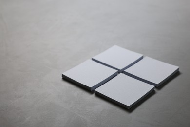 Blank paper sheets on grey textured table, closeup. Mockup for design