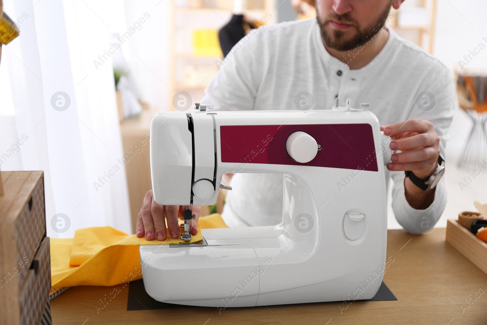 Photo of Fashion designer sewing new clothes with machine in studio, closeup