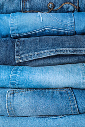 Stack of different jeans as background, closeup