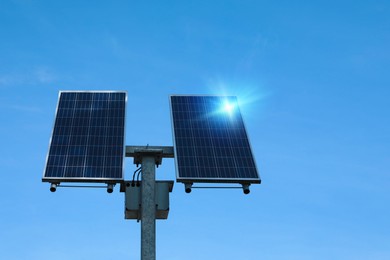 Modern solar panels against blue sky, low angle view. Alternative energy