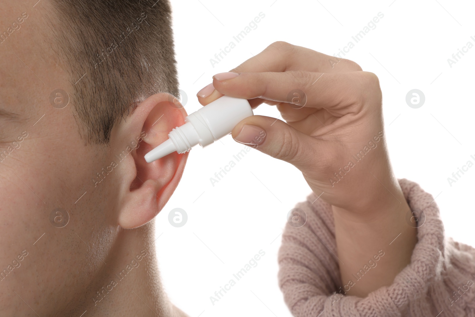 Photo of Woman dripping medication into man's ear on white background, closeup