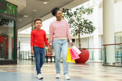 Photo of Family shopping. Happy mother and son with colorful bags in mall