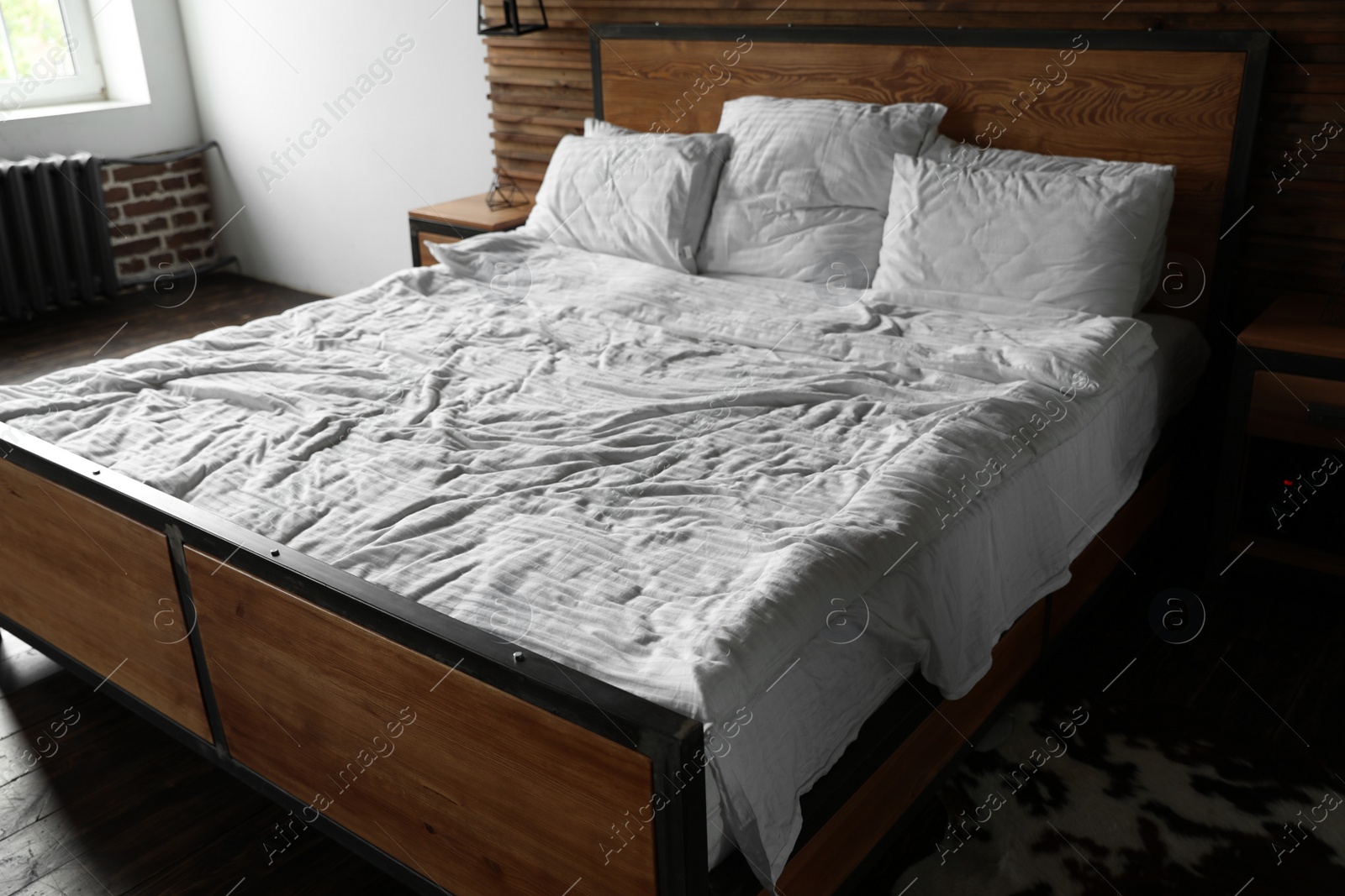 Photo of Comfortable bed with crumpled linen and pillows in stylish room interior