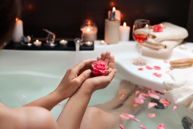 Photo of Woman holding rose flower while taking bath, closeup. Romantic atmosphere