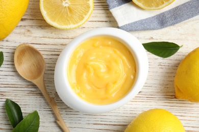 Photo of Delicious lemon curd in bowl on white wooden table, flat lay