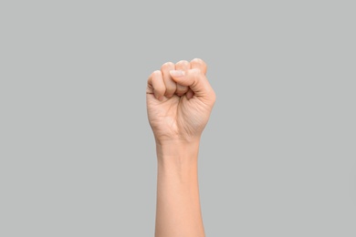 Photo of Woman showing S letter on grey background, closeup. Sign language