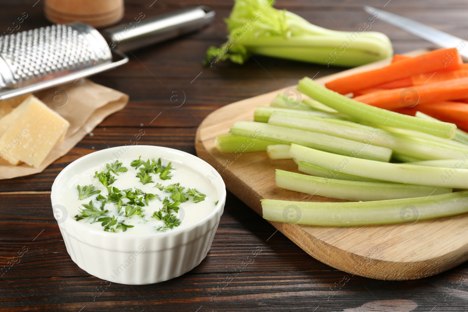 Photo of Celery and carrot sticks with dip sauce on wooden table, closeup