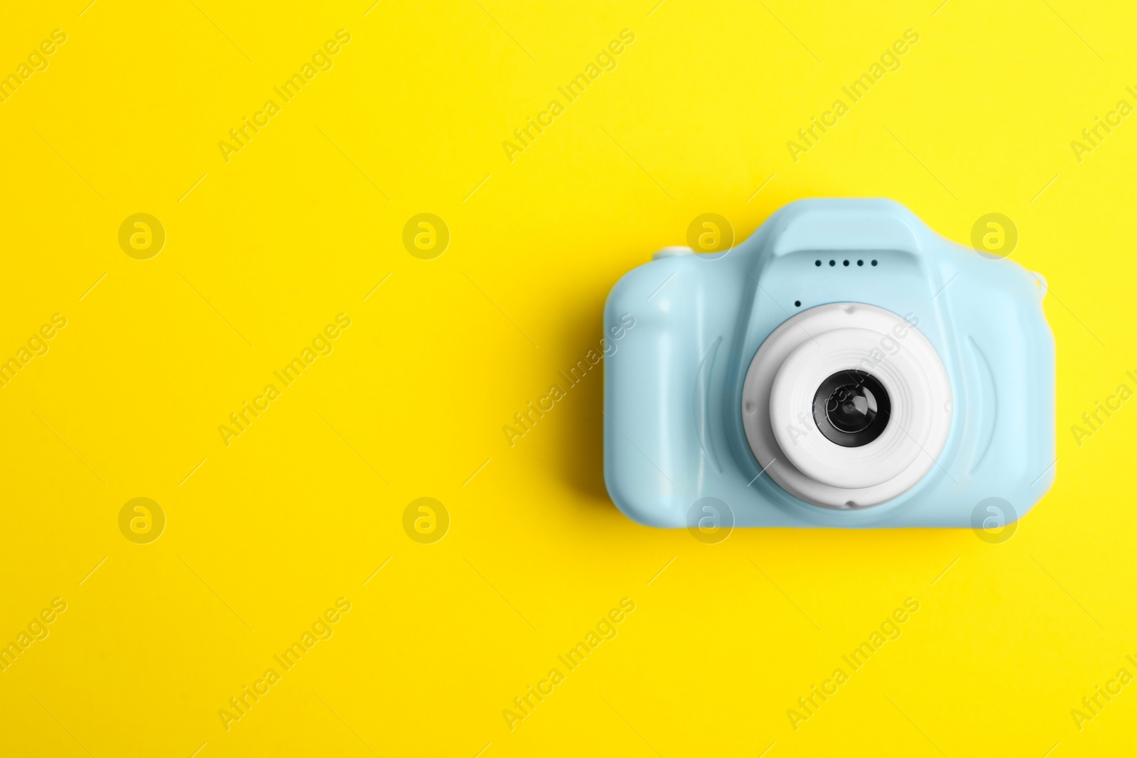 Photo of Light blue toy camera on yellow background, top view with space for text. Future photographer