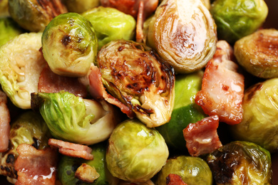 Delicious fried Brussels sprouts with bacon as background, closeup