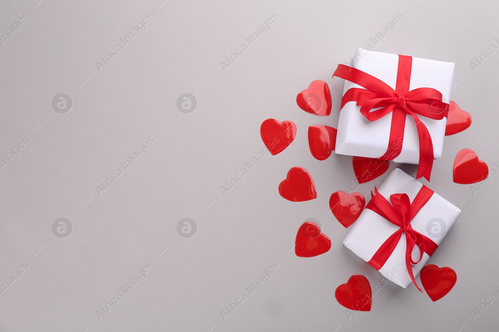 Photo of Beautiful gift boxes and hearts on grey background, flat lay with space for text. Valentine's day celebration