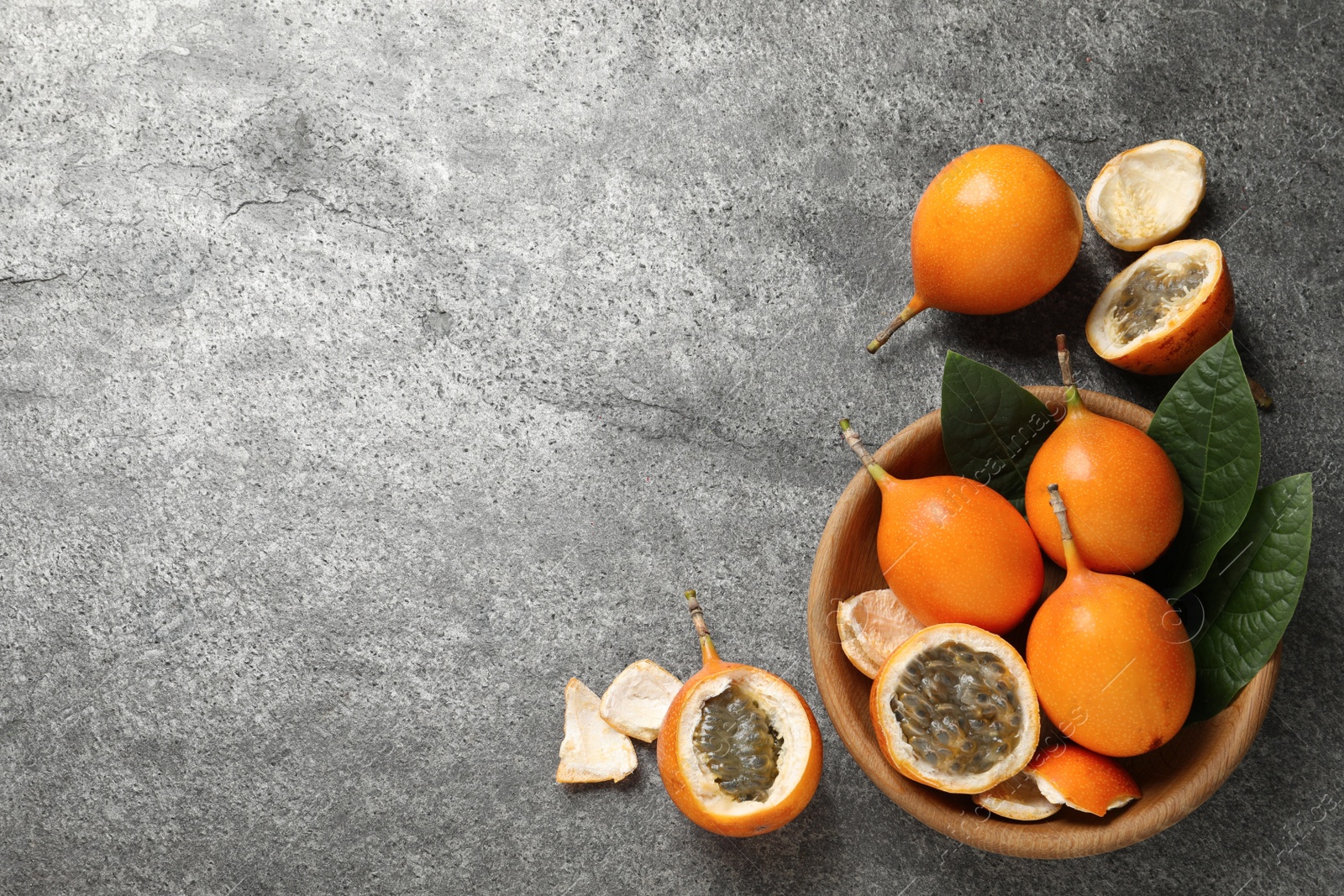Photo of Delicious ripe granadillas on grey table, flat lay. Space for text