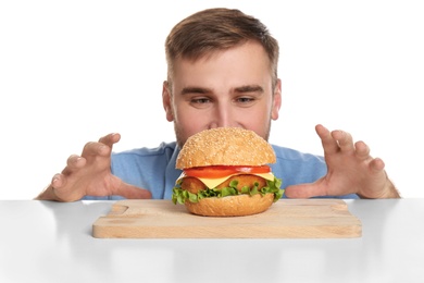 Young man and tasty burger on white background