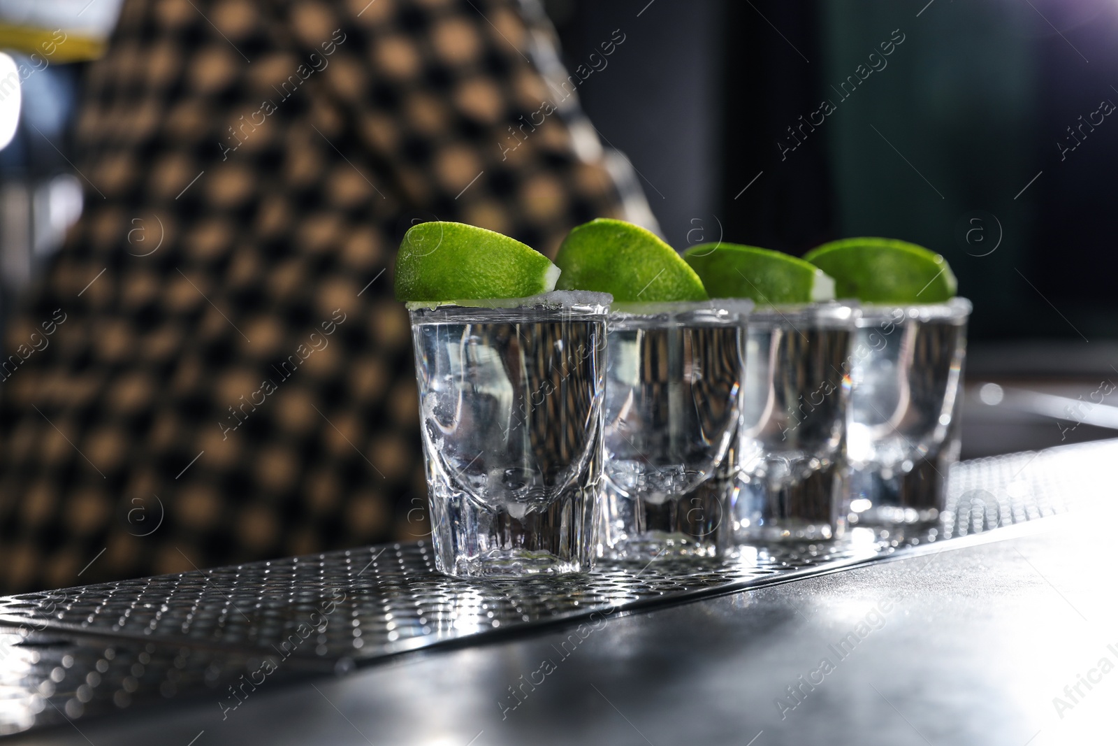 Photo of Mexican Tequila shots with lime slices on bar counter