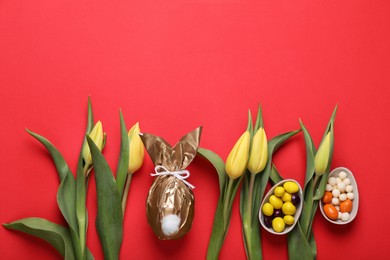 Flat lay composition with Easter bunny made of shiny gold paper and egg on red background. Space for text