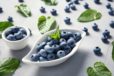 Photo of Juicy blueberries and green leaves on color table