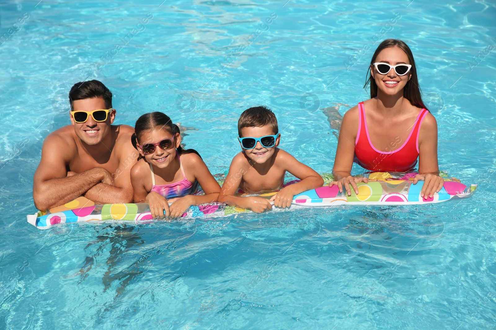 Photo of Happy family on inflatable mattress in swimming pool