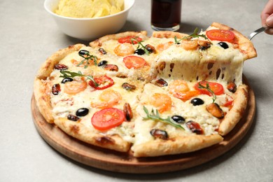 Taking slice of cheese pizza with seafood at grey table, closeup