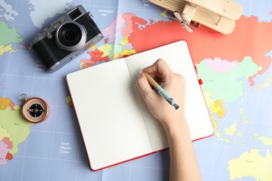 Photo of Woman planning vacation on world map, top view with space for text. Travel agency