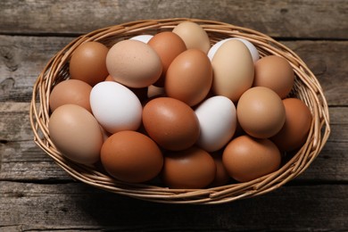 Fresh chicken eggs in wicker basket on wooden table, above view