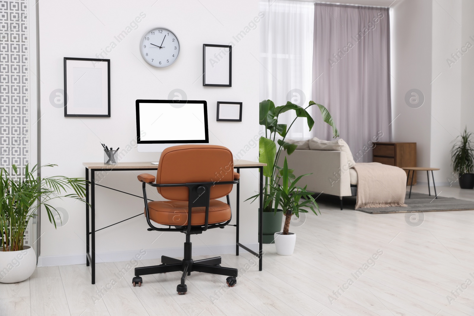 Photo of Stylish room interior with comfortable office chair, desk and houseplants