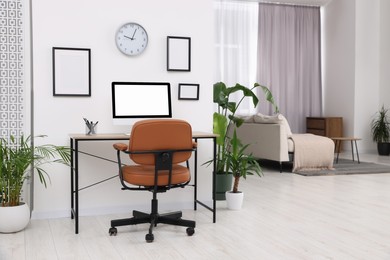 Stylish room interior with comfortable office chair, desk and houseplants