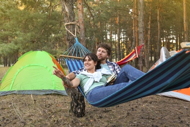 Photo of Lovely couple with book resting in comfortable hammock outdoors