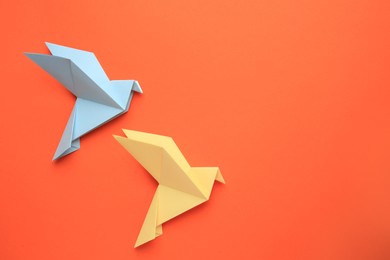 Photo of Beautiful colorful origami birds on orange background, flat lay. Space for text