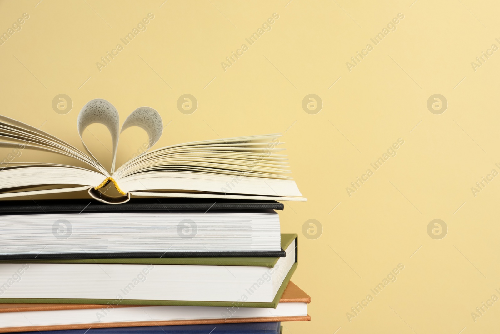 Photo of Stack of hardcover books on yellow background, space for text