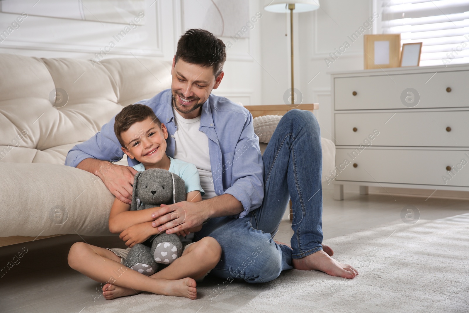 Photo of Happy father and his son on floor in living room. Adoption concept