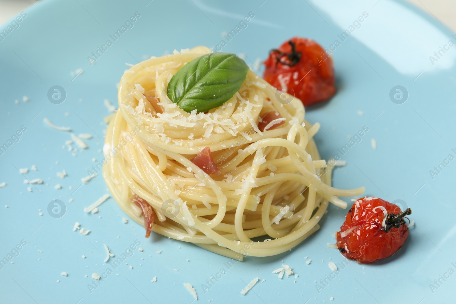 Photo of Tasty spaghetti with tomatoes and cheese on plate, closeup. Exquisite presentation of pasta dish