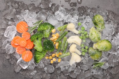 Photo of Different frozen vegetables with ice on grey table, flat lay