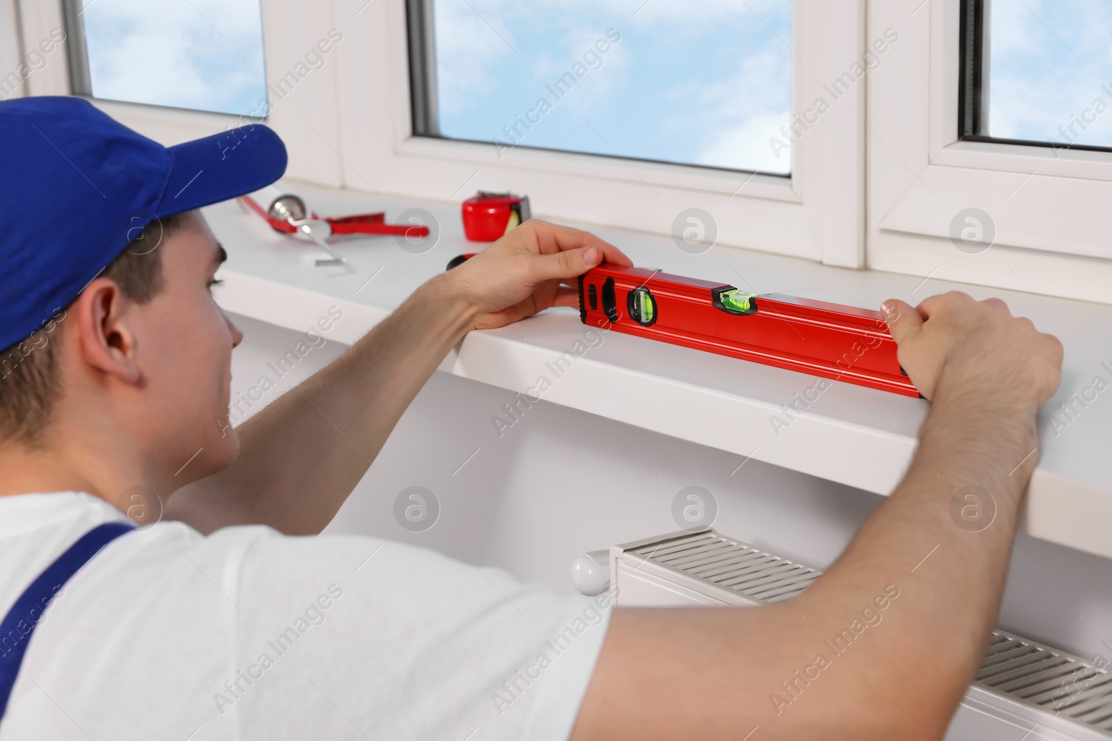 Photo of Worker using bubble level after plastic window installation indoors