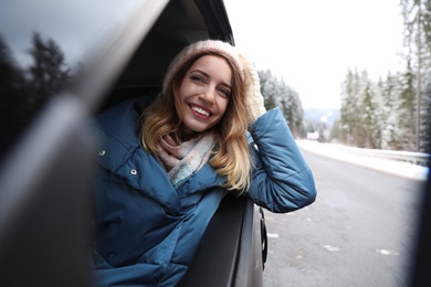 Photo of Young woman driving car and looking out of window on road. Winter vacation