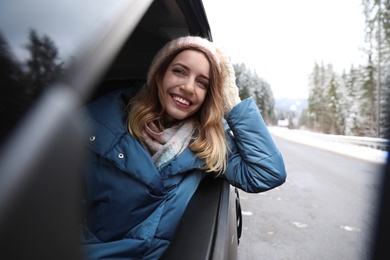 Young woman driving car and looking out of window on road. Winter vacation