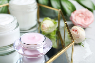 Open jars of cream and flowers on table