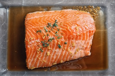 Photo of Raw salmon fillet with marinade in baking dish on table